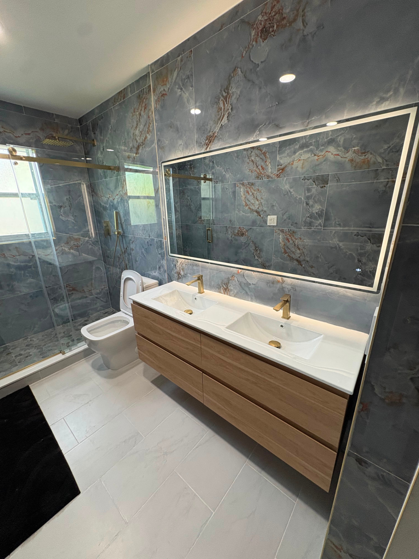 Completed bathroom remodel with large-format tile and glass shower enclosure.