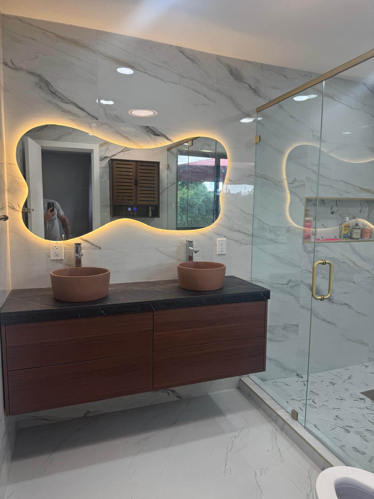 Completed bathroom remodel with floating double vanity, vessel sinks, illuminated mirrors and glass shower.
